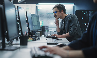 it person at desk using computer and multiple monitors