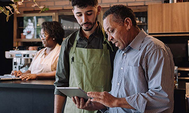 people looking at tablet together at coffe shop