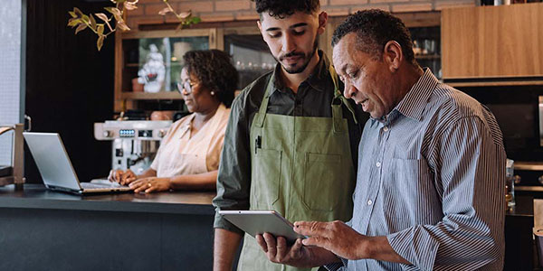 Two men standing and looking down at tablet