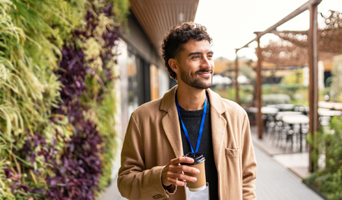 man walking outside next to a plant-covered building