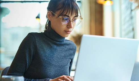 Woman with glasses working on laptop. 