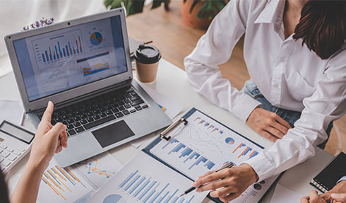 people meeting looking at laptop and documents with charts and graphs