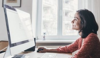 Woman in a sunny room looking at a computer screen.