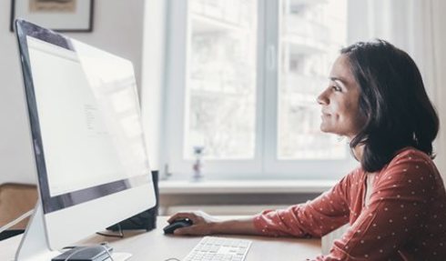 Woman in a sunny room looking at a computer screen.