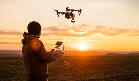 Person flying drone at sunset